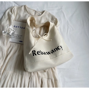 Detail of off-white canvas tote bag featuring black lettering and a delicate ribbon bow