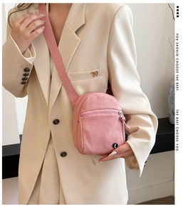 Detail of pink canvas crossbody bag with adjustable strap and front zipper pocket