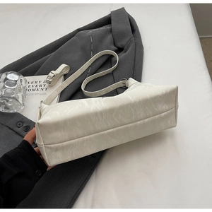 Detailed texture of white marble-embossed leather underarm bag on grey blazer background