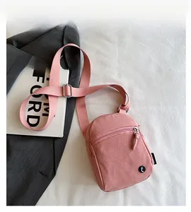 Close-up of pink casual crossbody bag with durable canvas texture and black logo