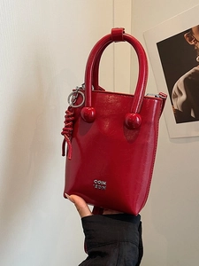 Sac seau chic en cuir rouge avec poignée et logo en métal sur texture de qualité