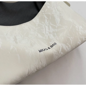 Detailed close-up of cream white pleated leather texture with MKXQ & BAG brand logo print