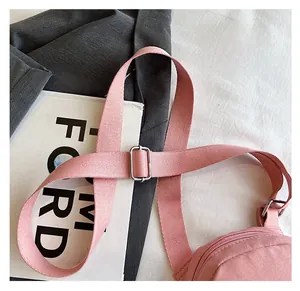Detail of adjustable wide shoulder strap and silver metal buckle on a pink crossbody bag