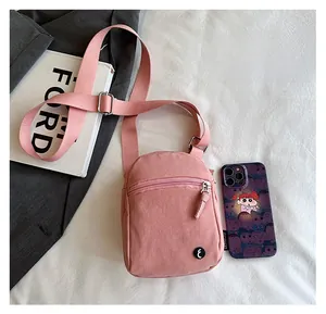 Pink casual crossbody bag showing size comparison with smartphone and book