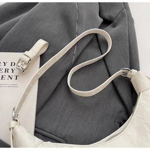 Macro detail of creamy white half-moon bag with cracked texture and silver buckle