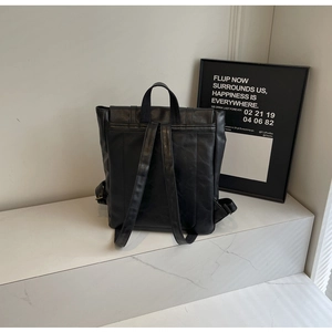 Detail view of the black leather backpack with adjustable straps and metal buckle on marble surface