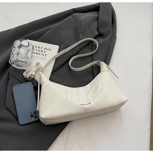 Detail of white marble textured leather underarm bag with black logo on a gray suit