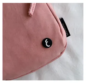Close-up of pink casual shoulder bag with black decorative buckle and logo side label