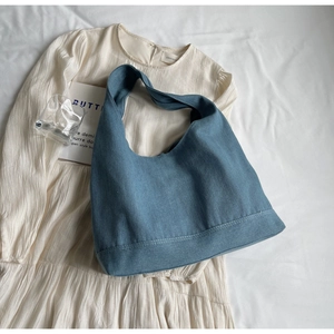 Detail shot of a large blue denim tote bag on minimalist aesthetic background