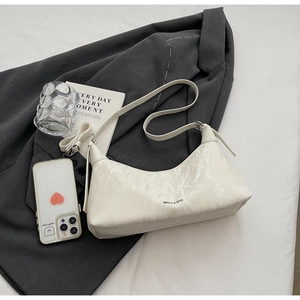 Detail of white marble-textured underarm bag displayed on a grey suit with slim strap