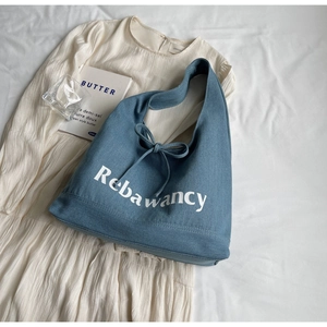 Close-up of blue denim tote bag with Rebawancy script logo and stylish bow tie detail