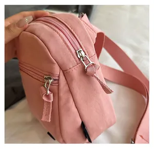 Close-up of dual smooth zippers and pink fabric texture on a compact shoulder bag