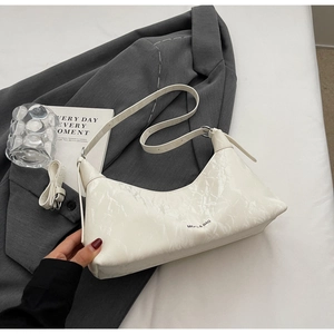 Detailed close-up of white glossy pleated texture and adjustable strap on underarm bag