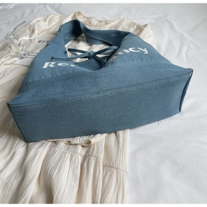 Detailed view of large denim tote bag with white Recy print and stylish knot closure