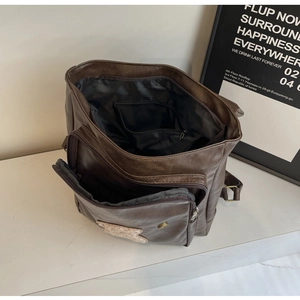 Macro view of the open brown PU leather backpack showing black lining and inner pocket