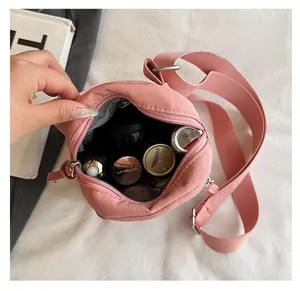Internal view of pink round shoulder bag showing storage for cosmetics and wide strap