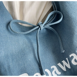 Detailed macro view of denim fabric texture with white lettering and a neat drawstring bow