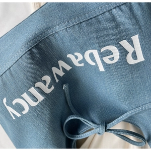 Close-up of blue denim fabric with white Rebawancy print and drawstring details