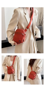 Detail of a bright orange canvas crossbody bag with adjustable wide strap and front zipper