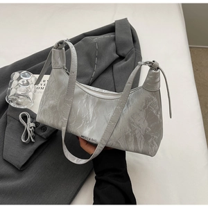 Close-up of textured grey dumpling bag with metallic finish and brand logo detail