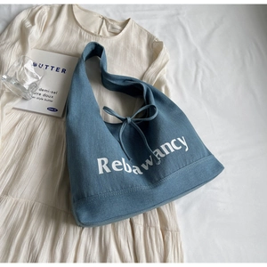 Close-up of denim tote bag with Rebawancy print and decorative bow drawstring detail