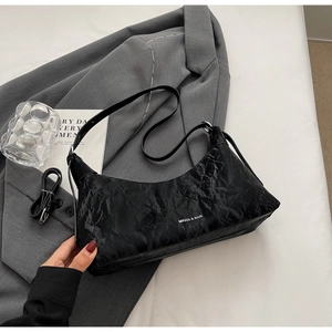 Detailed view of black textured shoulder bag with unique crinkled finish and white logo