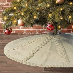 Crèmewitte gebreide kerstboomschort met kabelpatroon op een donkere houten vloer