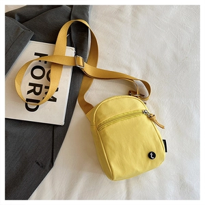 Close-up of bright yellow nylon crossbody bag with front zipper pocket and logo