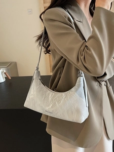 Elegant silver textured underarm bag with zipper closure shown on a model in a suit