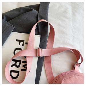 Detailed shot of pink crossbody bag with wide adjustable strap and metallic hardware