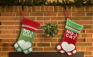 Détail de chaussettes de Noël tricotées pour chat et chien devant une cheminée en brique