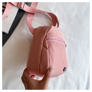Detail of pink nylon crossbody bag featuring double zipper pockets and wide strap
