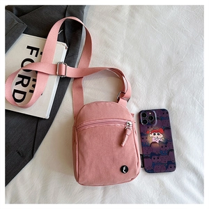 Detailed view of pink canvas crossbody bag with dual zipper pockets and adjustable strap