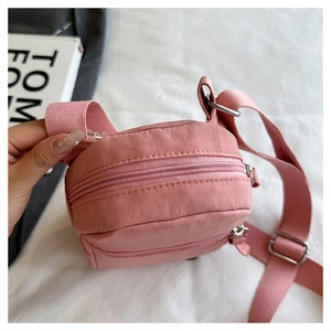 Detail of pink nylon crossbody phone bag with double zippers and wide shoulder strap