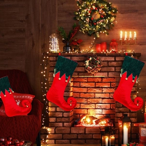 Trois chaussettes de Noël lutin en velours avec cloches près d'une cheminée