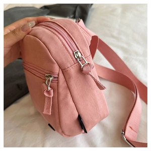 Close-up of pink casual nylon shoulder bag featuring dual zippers and adjustable strap