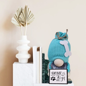 Dettaglio di uno gnomo blu a maglia con un cartello Home Is Where The Dogs Are