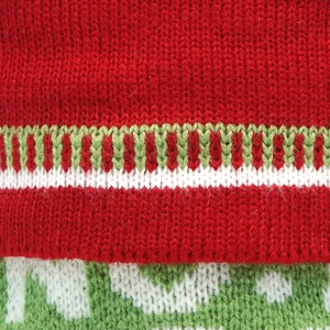 Gros plan du tissu de chaussette de Noël avec des motifs de vagues tricotés en rouge et vert