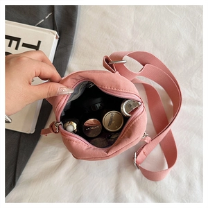 Detail view of pink nylon crossbody bag interior showing storage for cosmetics and essentials