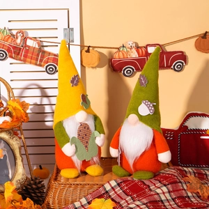 Detail of fall harvest gnomes with felt hats and autumn leaves in a cozy rustic setting