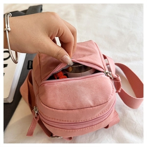 Pink nylon crossbody bag interior showing lipstick storage and layered zipper design