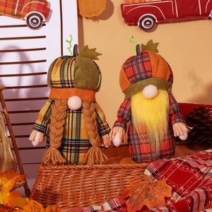 Close-up of plush harvest gnomes with pumpkin hats on a basket with autumn decor