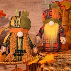 Close-up of plush harvest gnomes with pumpkin hats and plaid outfits on maple leaves