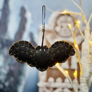 Detail of a black felt bat ornament with yellow stitching for Halloween hanging decor