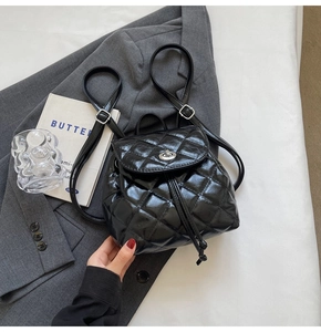 Detail of black quilted mini backpack with glossy finish and silver twist-lock closure