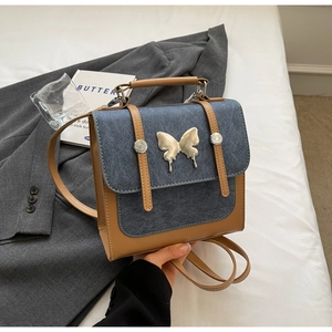 Detail of blue denim and brown leather stitching bag with silver butterfly buckle