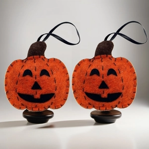 Detail of two plush Halloween pumpkin hangings with black felt Jack-o'-lantern faces