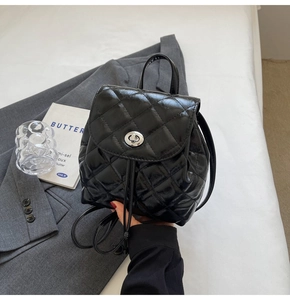 Macro detail of black quilted mini backpack featuring silver twist lock and polished finish