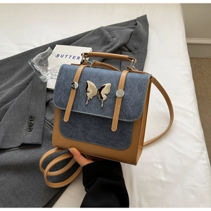 Close-up of contrast design handbag with blue denim flap and silver butterfly logo