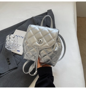 Detail of silver quilted backpack with metallic finish and round twist lock closure